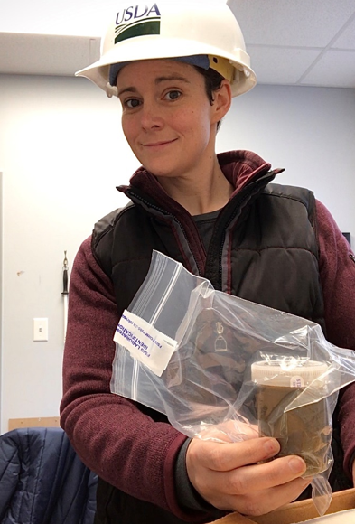 Woman wearing hardhat holds ziploc bag