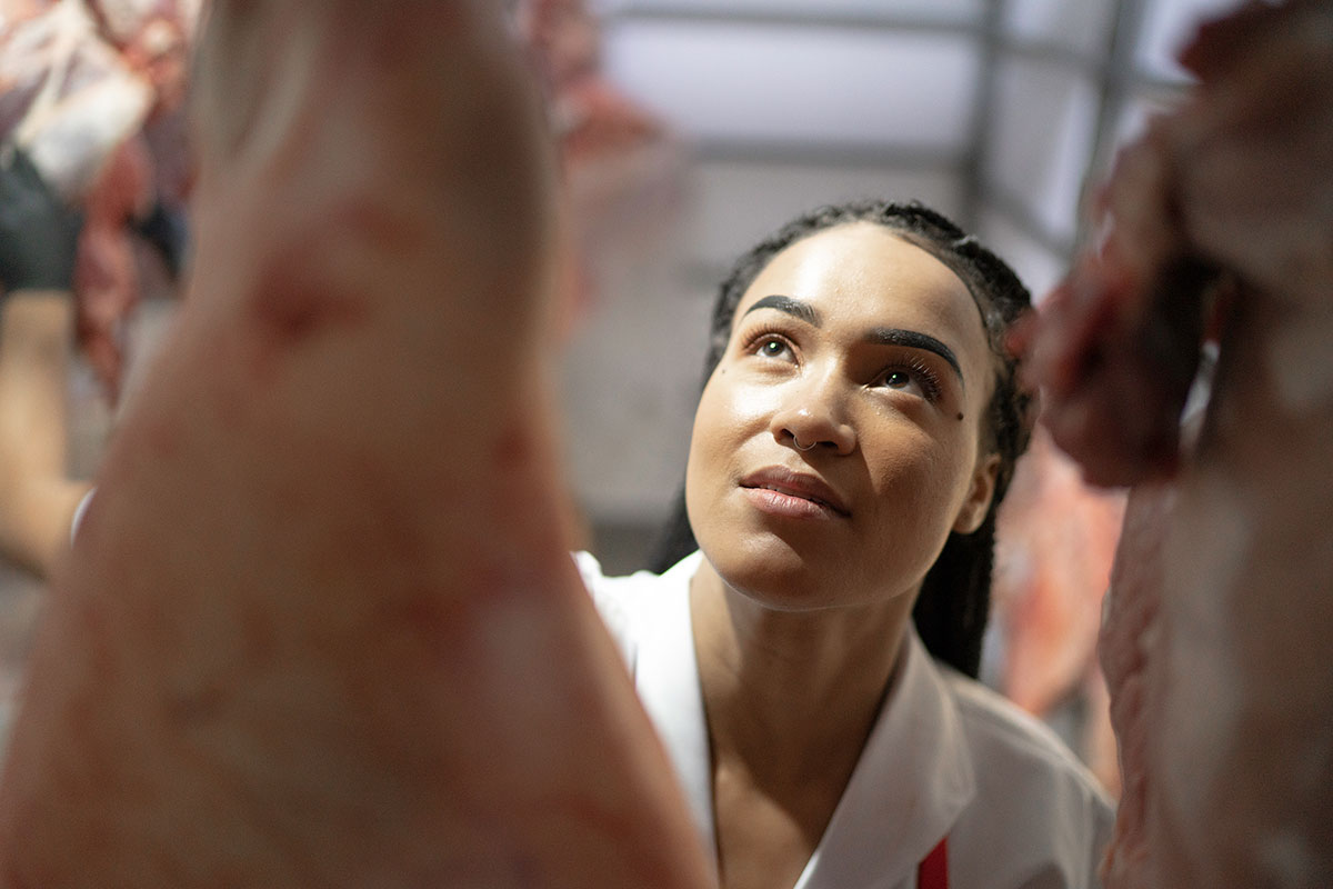 Woman inspecting hanging raw meat
