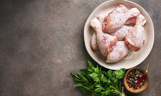 Raw chicken on plate with ingredients laying near.