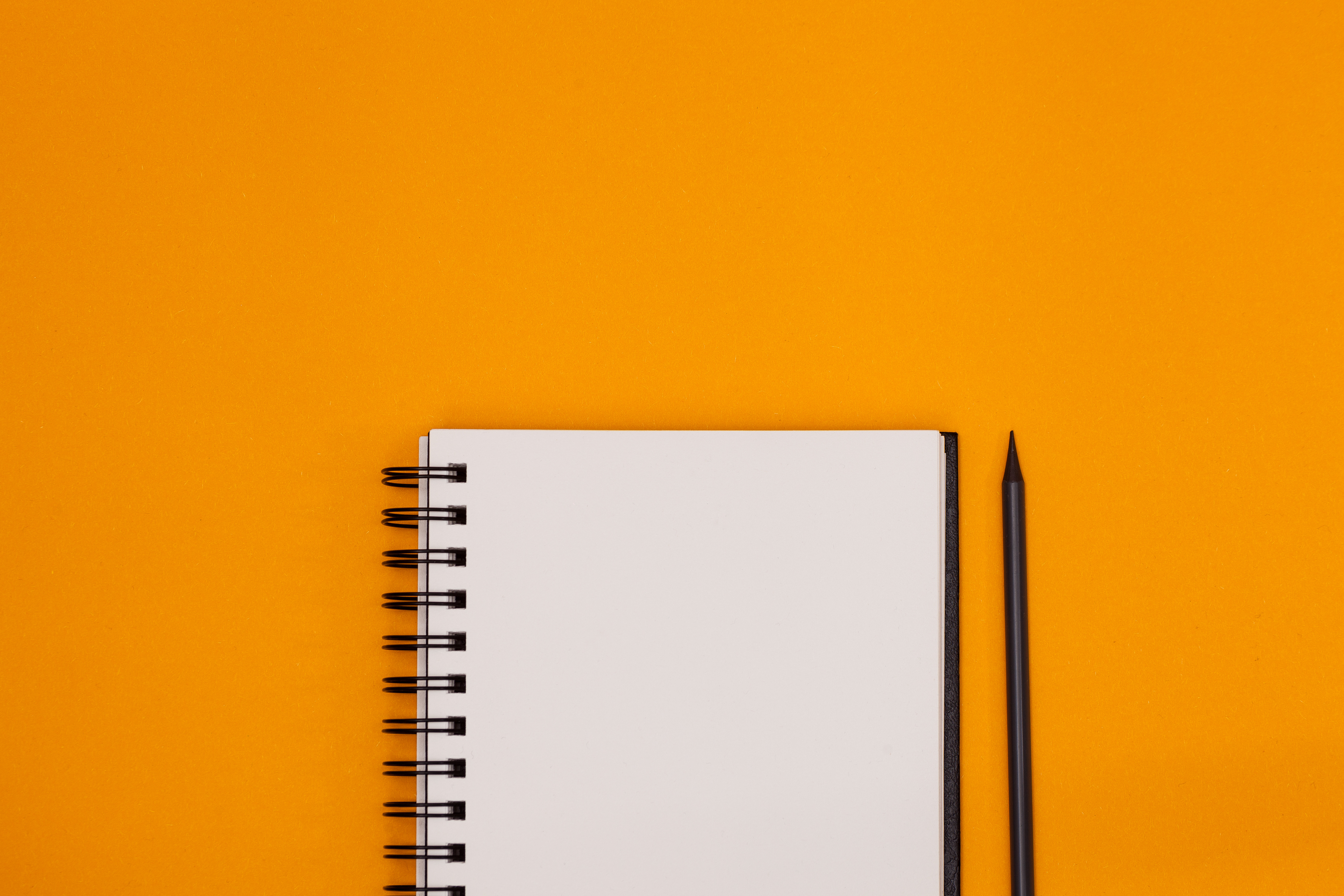 Notebook and pencil with orange background