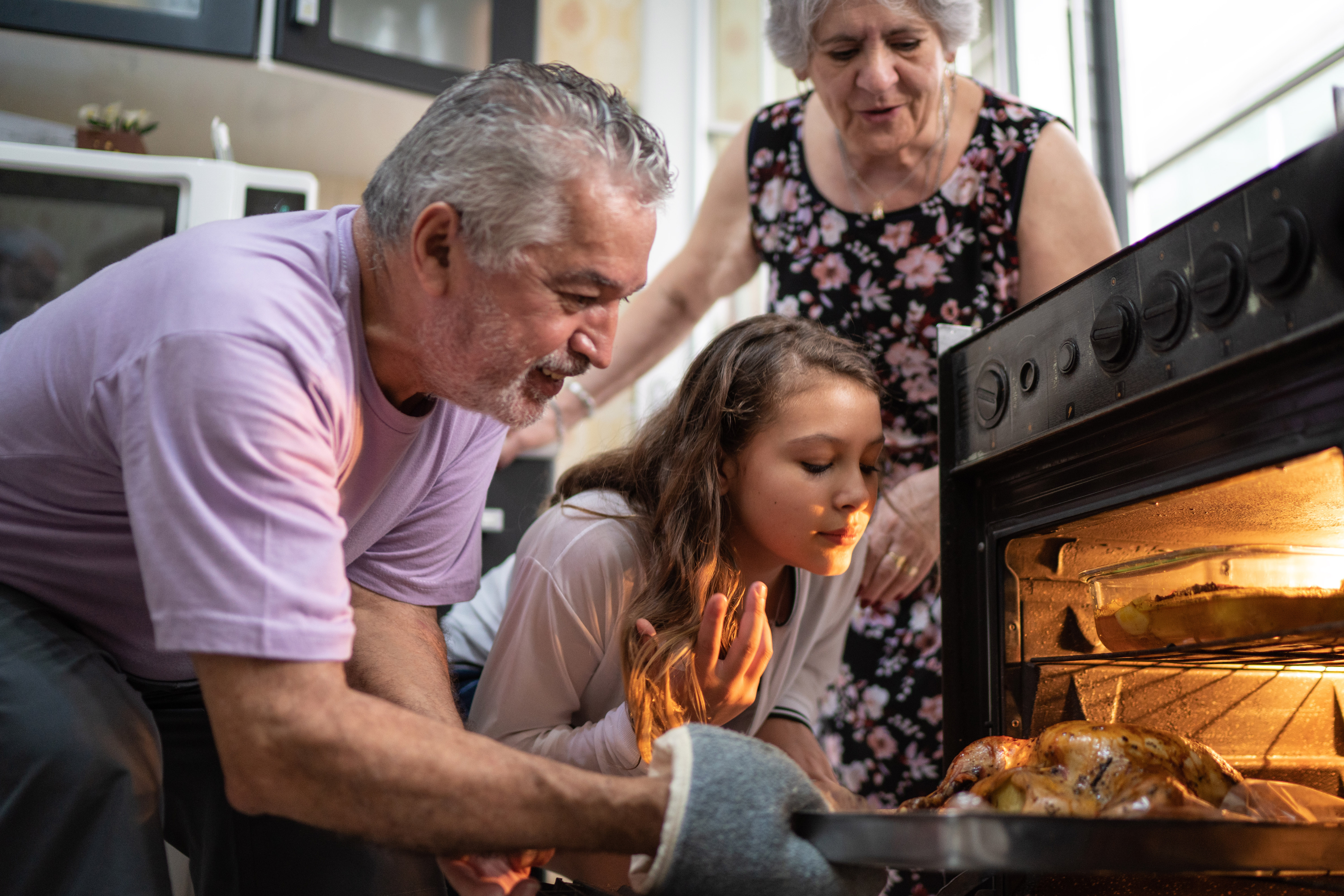 Family taking turkey out of oven