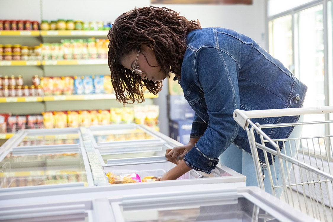 Woman looking at food labeling in refrigerated section in grocery store